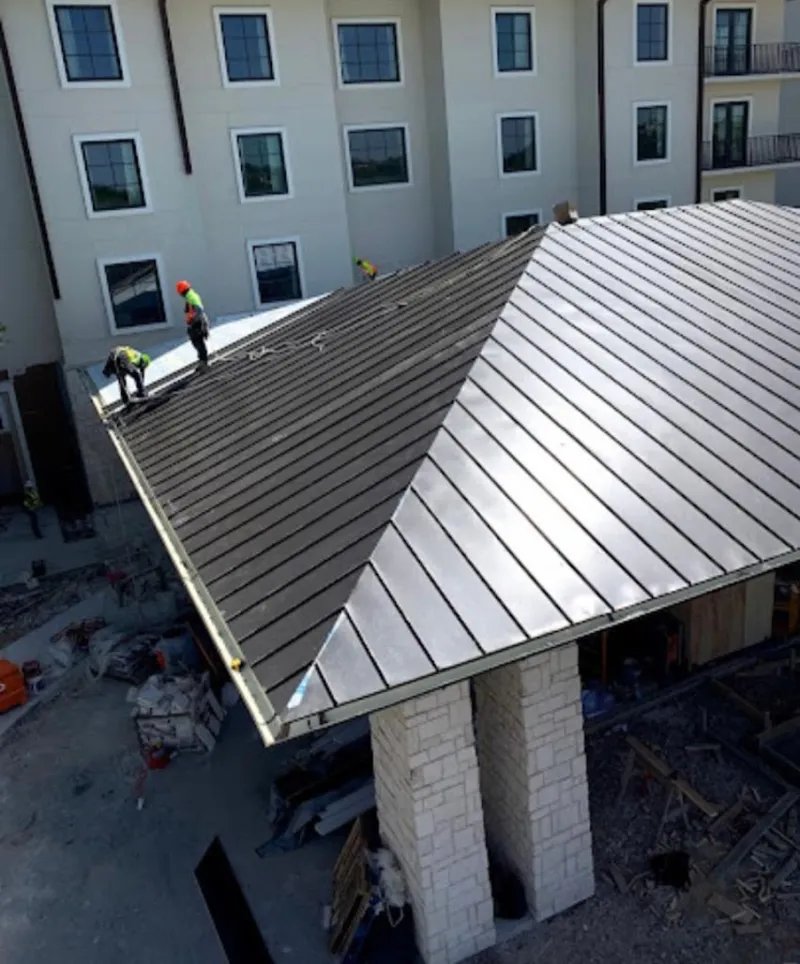 Crew installing standing seam metal roof panels on a commercial project in Farmers Branch